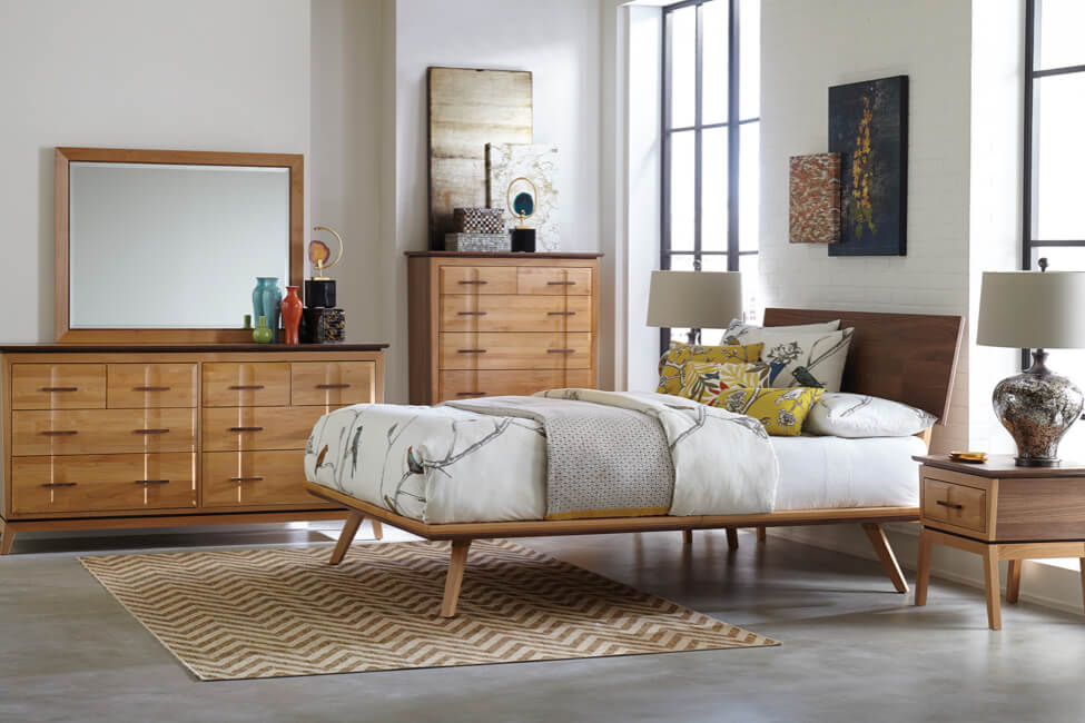 Modern bedroom with wooden furniture set, patterned rug, and decorative lamps.